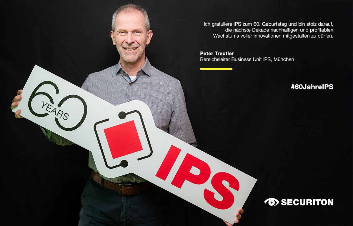 Eine Person hält das 60 Jahre IPS Logo in den Händen. Rechts daneben steht ein Glückwunsch zum Geburtstag.